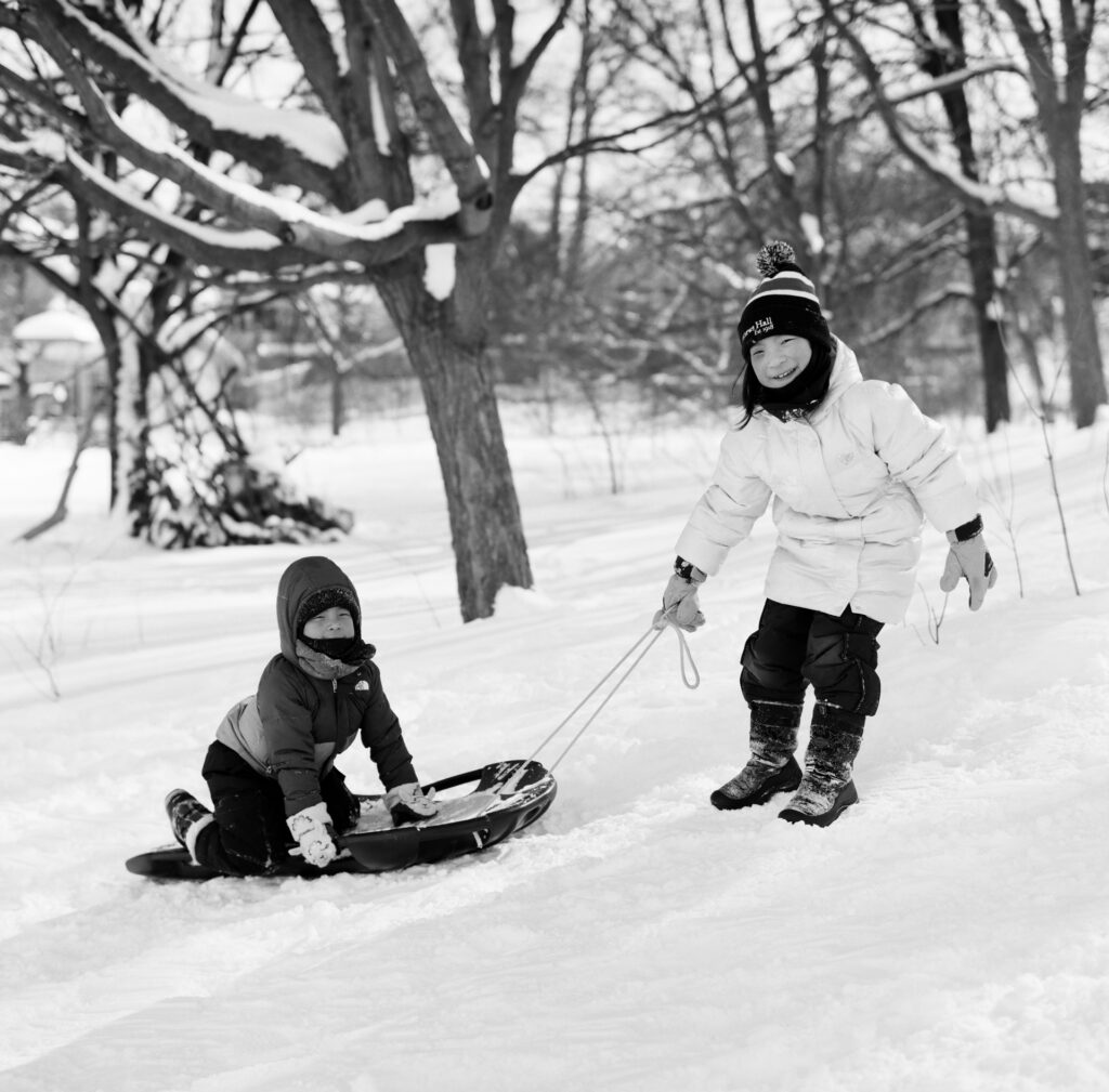 Girl pulling boy on Sled