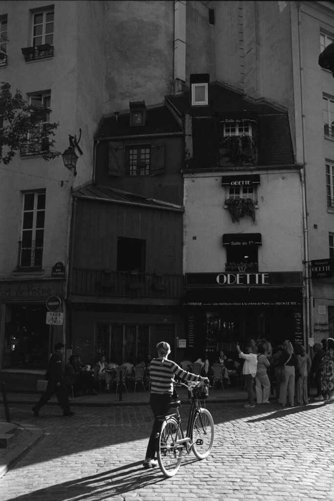 A person pushing a bicycle along a Parisian street