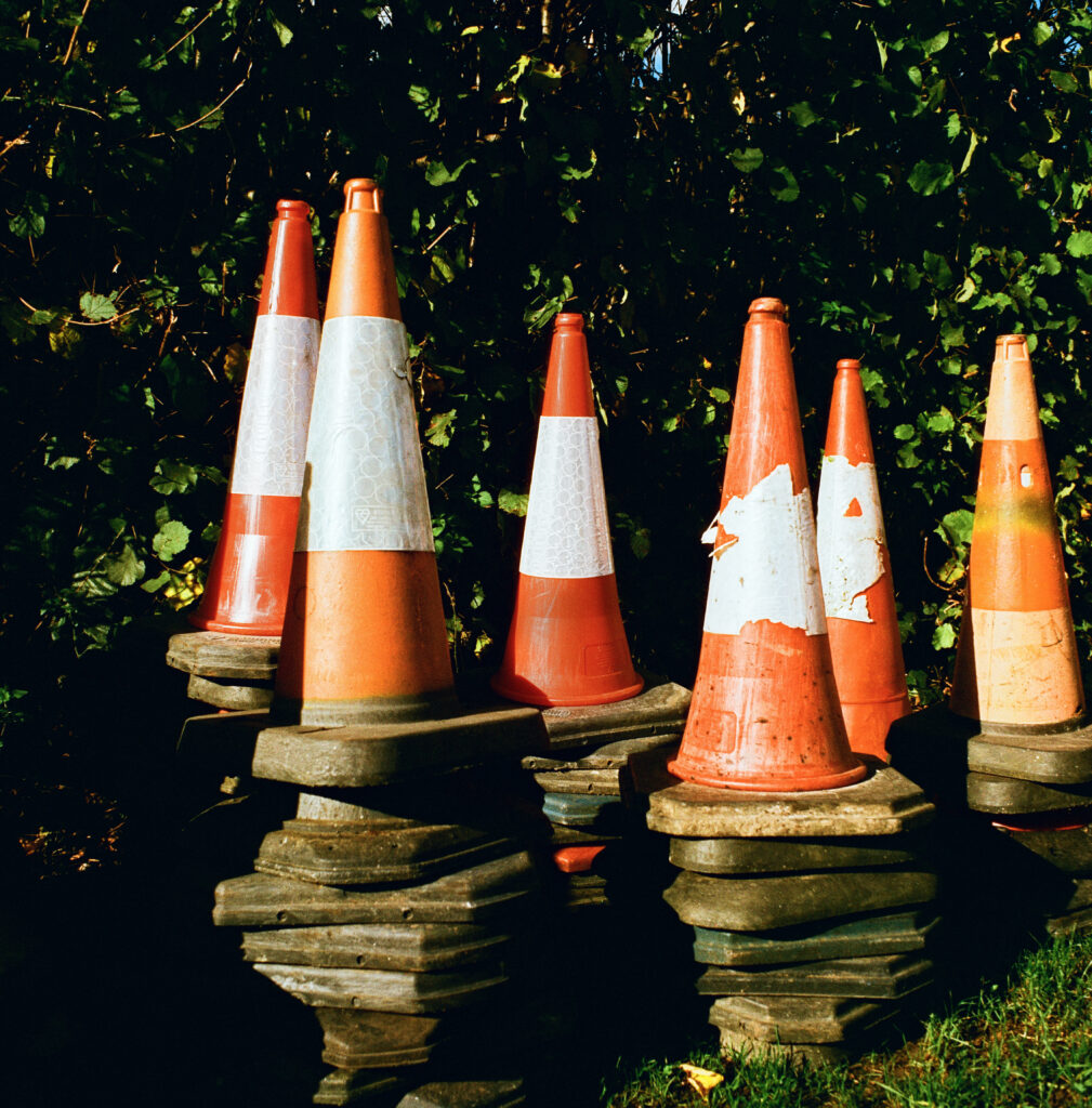 A set of old traffic cones stacked next to a bush that I found on a walk around Bishops Waltham